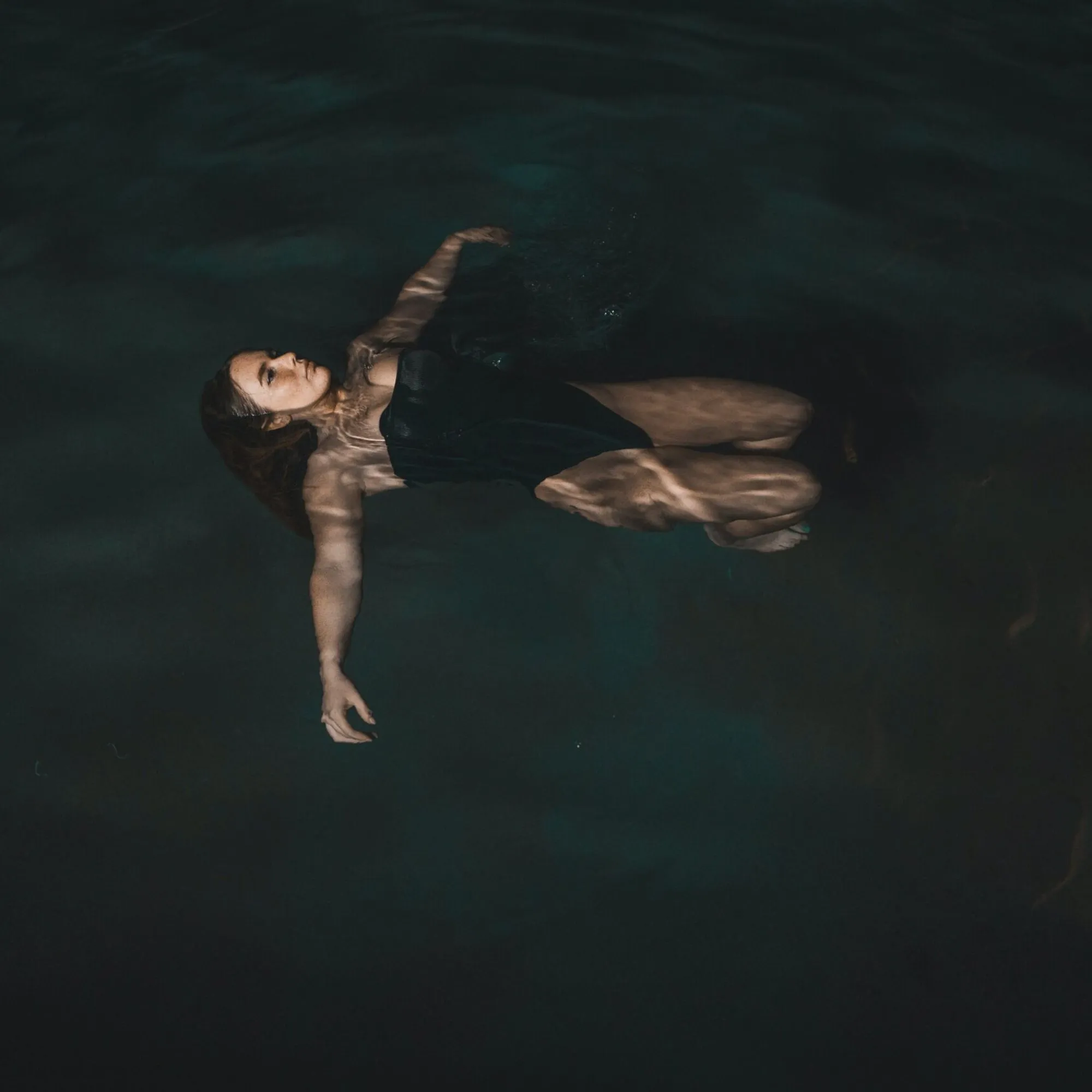 Woman floating in a dimly lit body of water